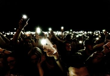 crowd holding smartphone while in flashlight