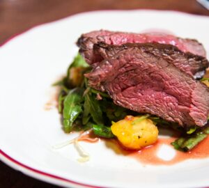 medium rare sliced steak in white ceramic plate