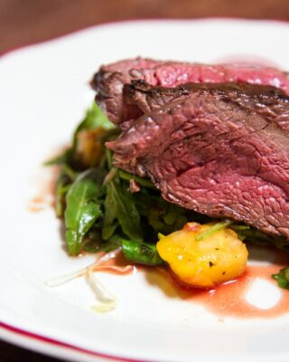 medium rare sliced steak in white ceramic plate