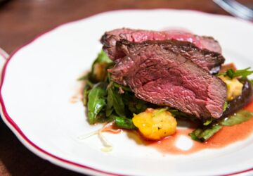 medium rare sliced steak in white ceramic plate